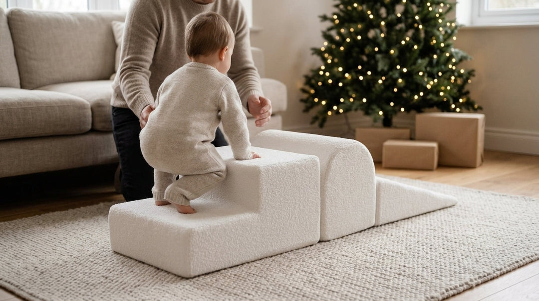 Toddler climbing a white foam soft play set in a living room at Christmas