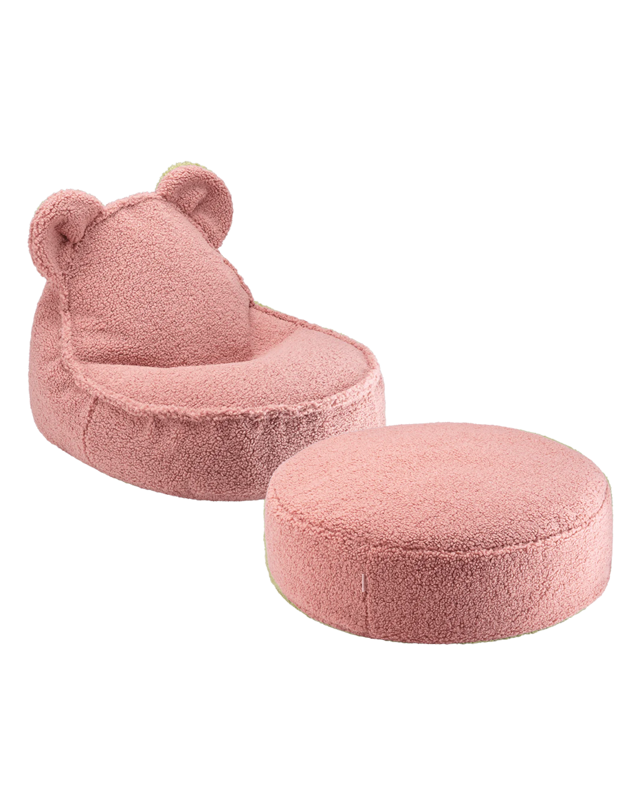 Child seated on pink Wigiwama ottoman reading, cream bear chair and yellow pouf nearby