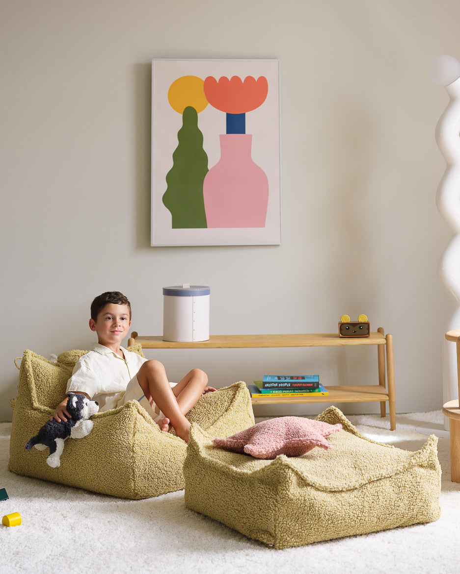 Child reading in yellow Wigiwama beanbag with pink ottoman in playroom setting