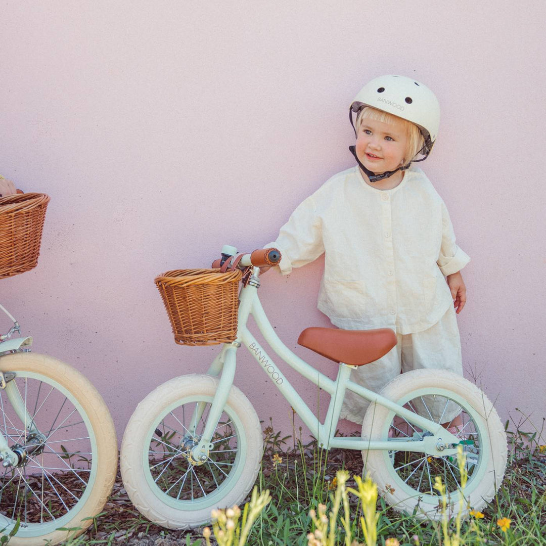 Child riding pale mint balance bike outdoors, wearing coordinating helmet and white top