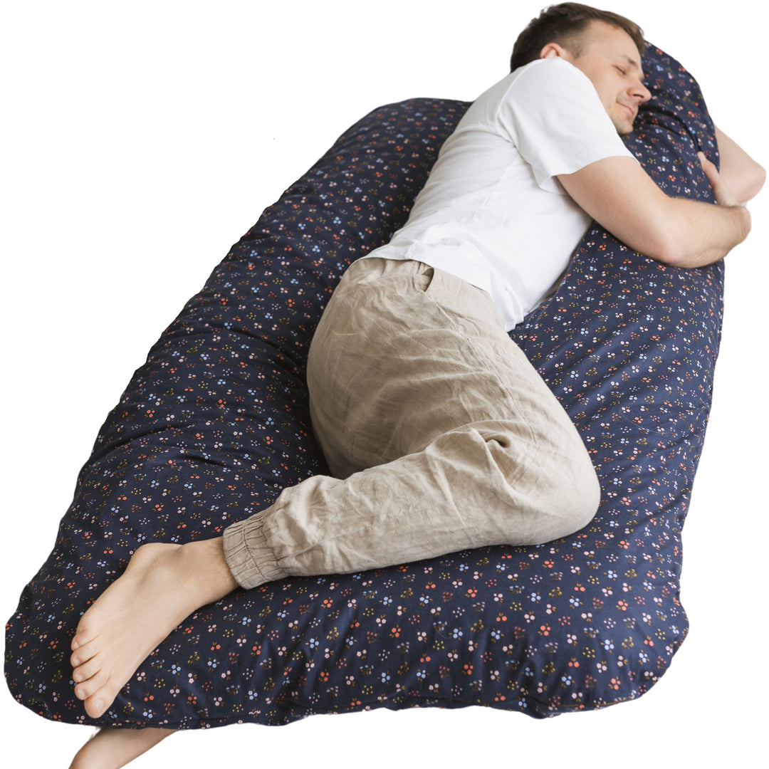 Man sleeping wrapped in the MINICAMP U-shaped comfort pillow in navy floral print
