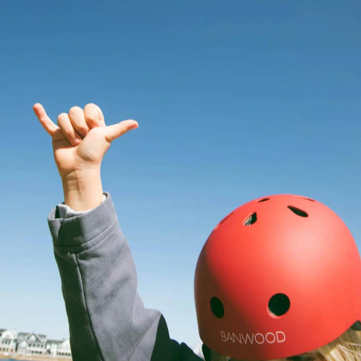 Child wearing the Banwood Classic Helmet in Matte Red outdoors against a blue sky