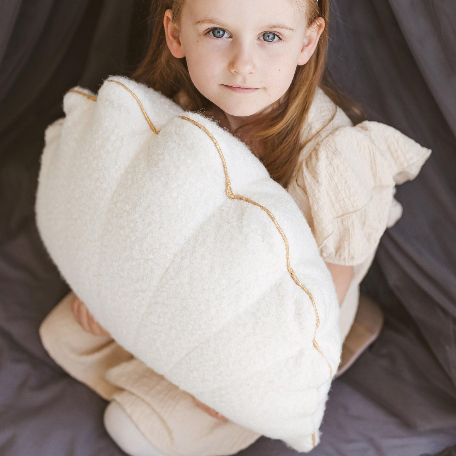 Ecru bouclé seashell cushion with golden metallic trim, front view