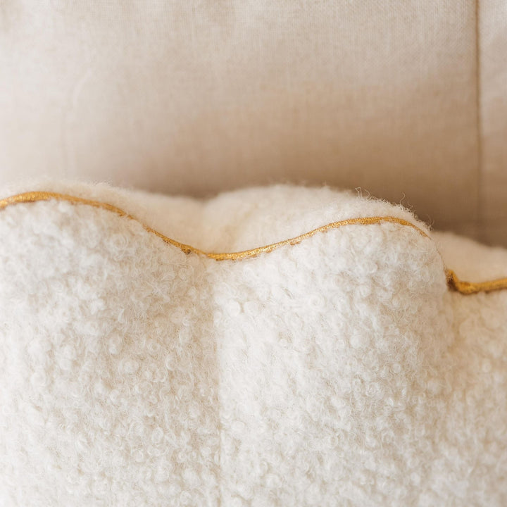 Close-up of golden metallic trim on ecru bouclé seashell cushion