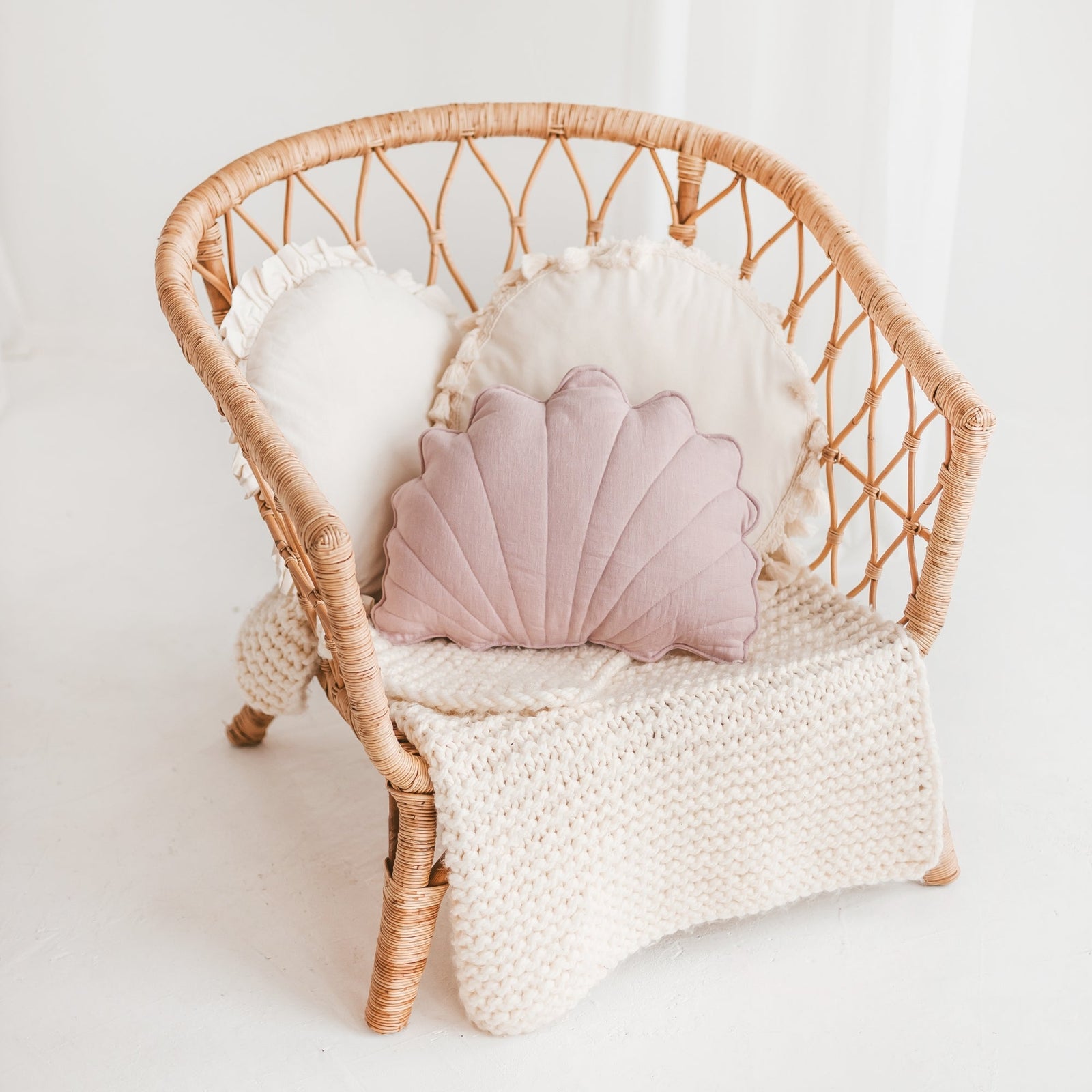 Pink starfish-shaped cushion from the MINICAMP coastal cushion range on a rattan chair