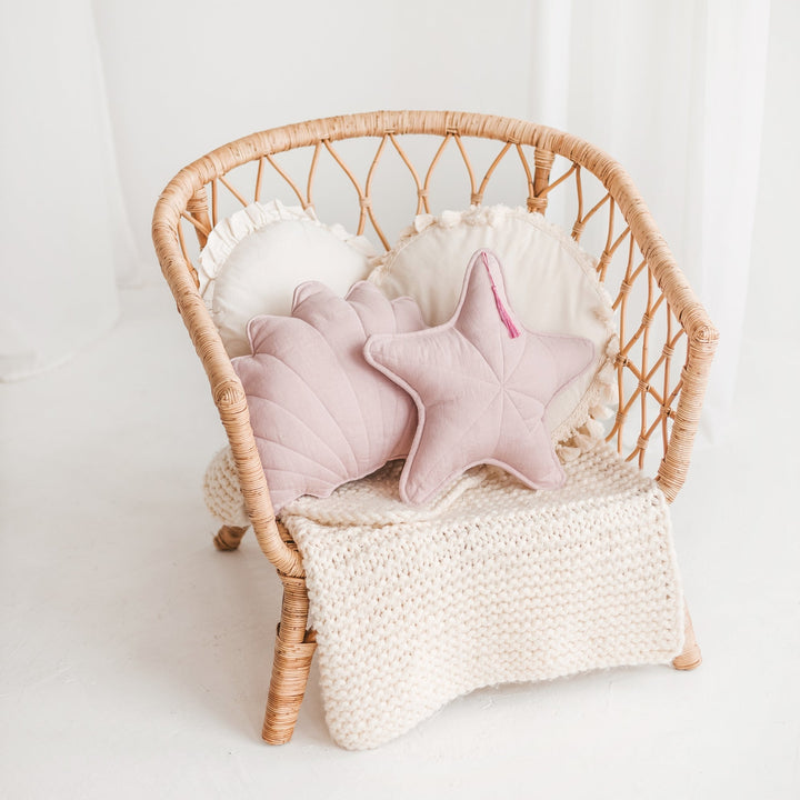 Pink linen seashell and starfish cushions styled together on a rattan chair