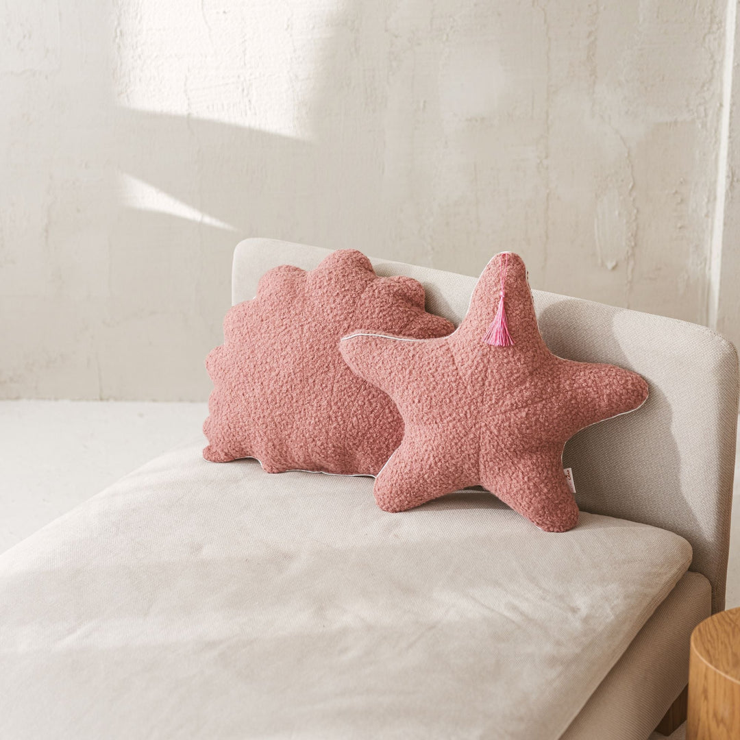 Rose bouclé seashell and starfish cushions styled together on a sofa