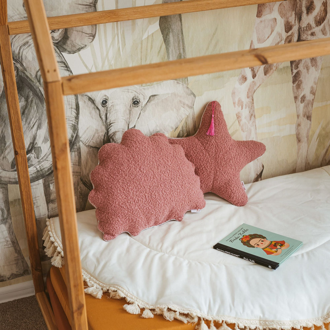Rose bouclé starfish and seashell cushions styled together on a bed