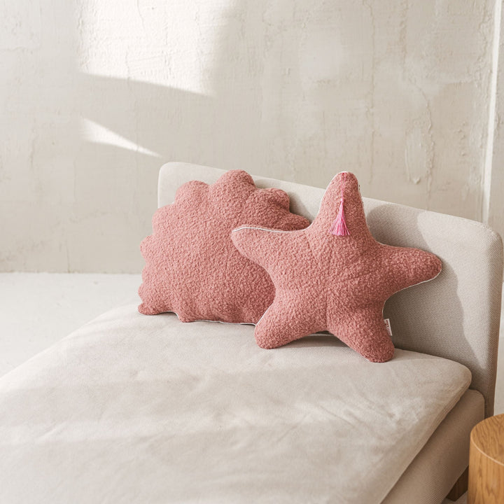 Rose bouclé starfish and seashell cushions styled together on a sofa