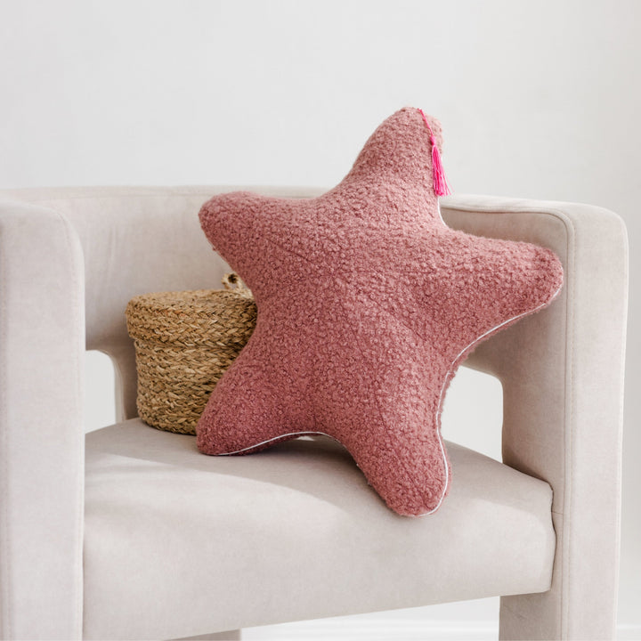 Rose bouclé starfish and seashell cushions styled together on a bed in a safari-themed nursery