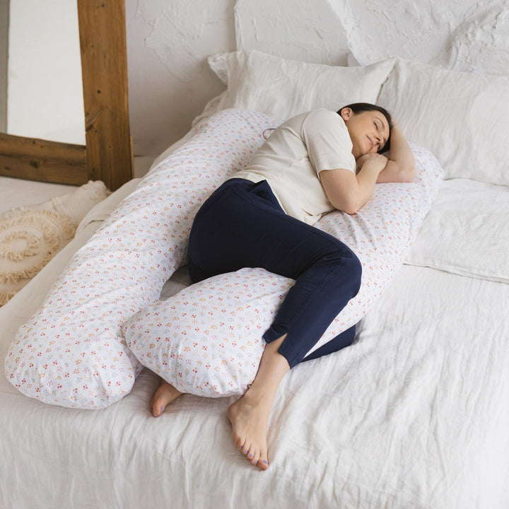 MINICAMP U-shaped maternity pillow with a printed cover option, displayed on a bed in a real bedroom