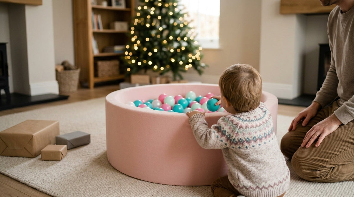 Toddler playing in a powder pink round ball pit on Christmas morning
