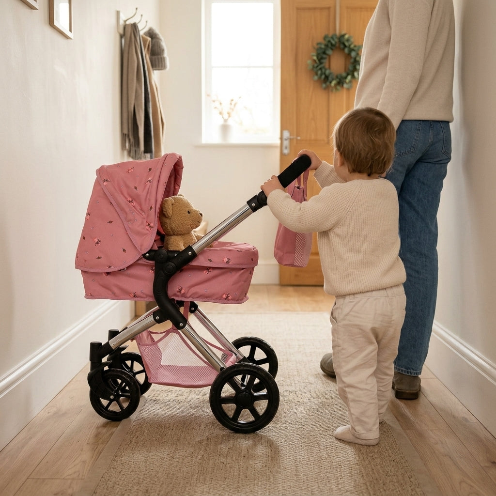 Toddler pushing a pink dolls pram with a teddy along a hallway