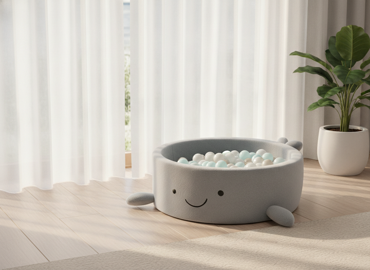MeowBaby Dusty Ice Blue boucle whale ball pit beside a window with sheer curtains and a potted plant