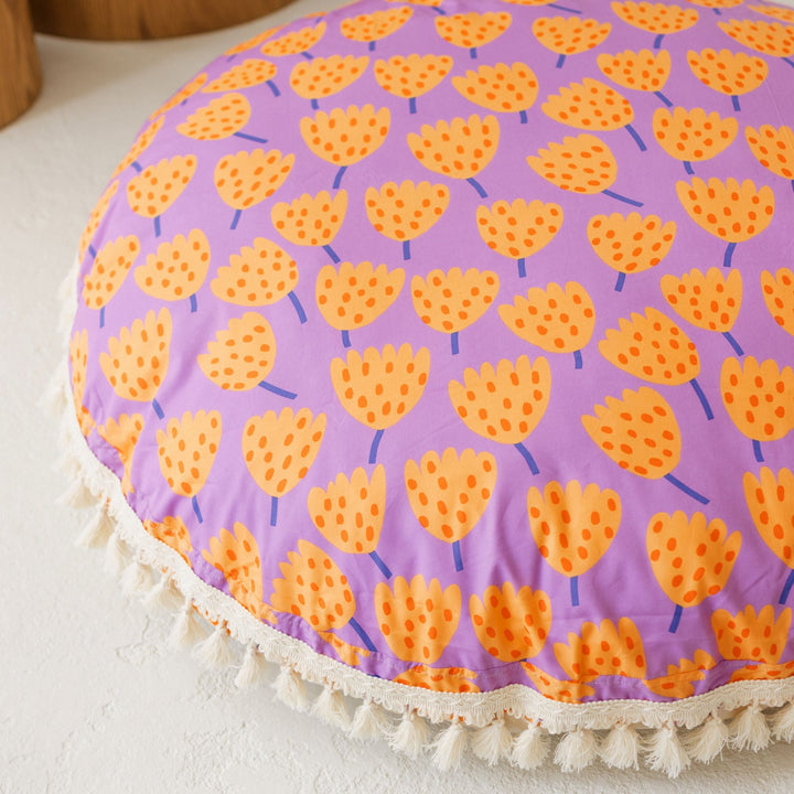 Close up of the tulip pattern and cream tassel trim on the MINICAMP floor cushion