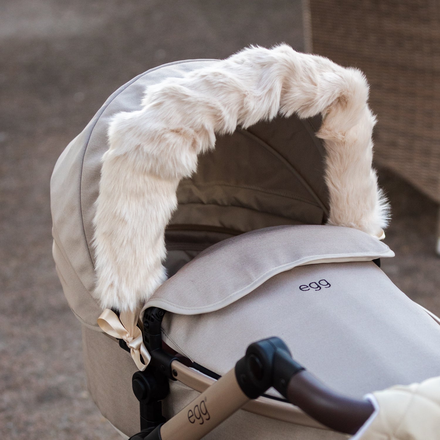 Roma Dolls Pram Hood Fur in feather colourway, ribbon-tied to an egg dolls pram hood