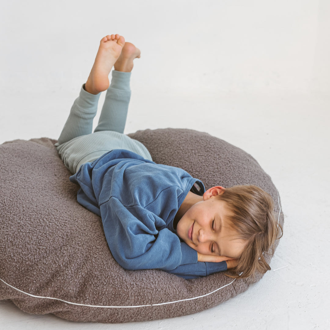 MINICAMP grey boucle floor cushion used as a floor chair