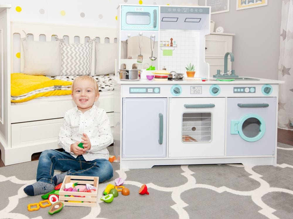 A child playing with the MeowBaby Grey &amp; Teal Wooden Play Kitchen and pretend food props (props not included)
