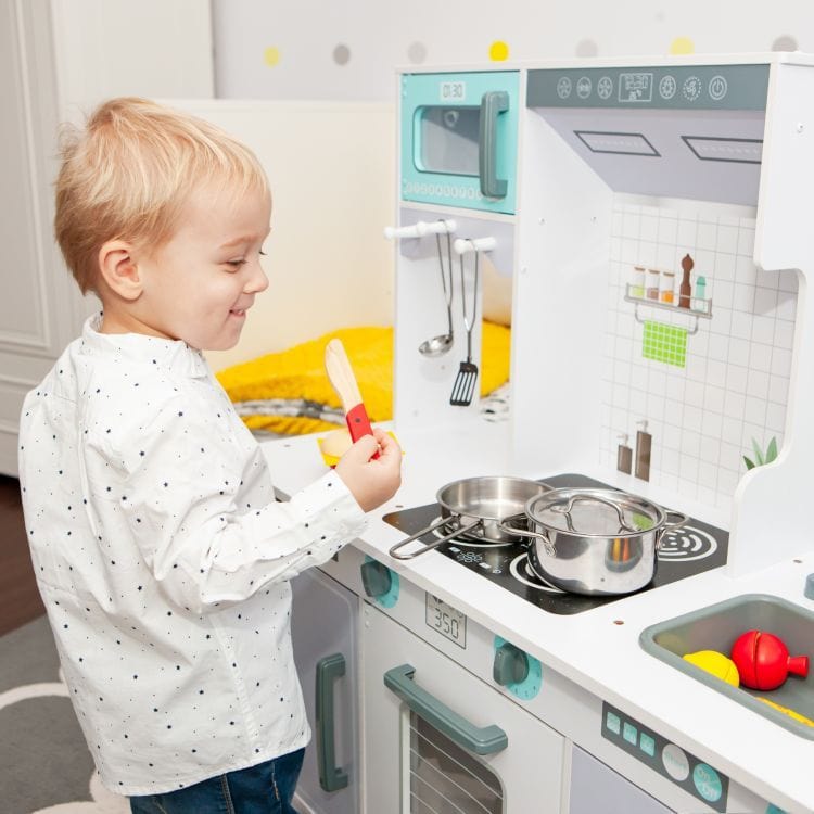 A child cooking with a wooden spatula at the MeowBaby Grey &amp; Teal Wooden Play Kitchen