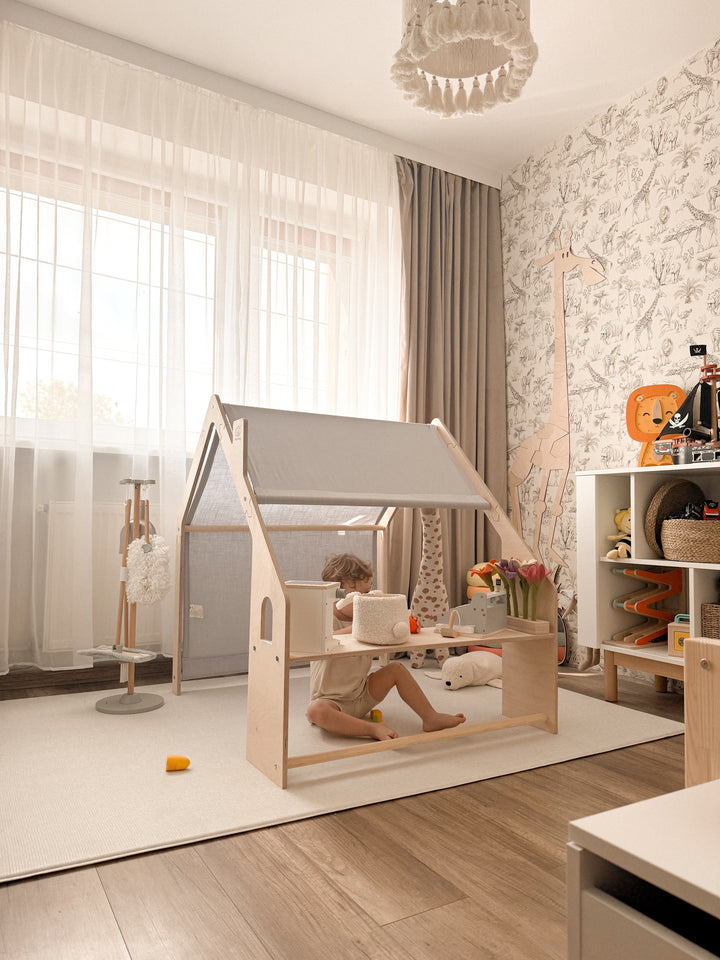 Child sitting inside the MeowBaby Wooden Playhouse in a bedroom, natural wood frame with the grey-blue canopy roof up