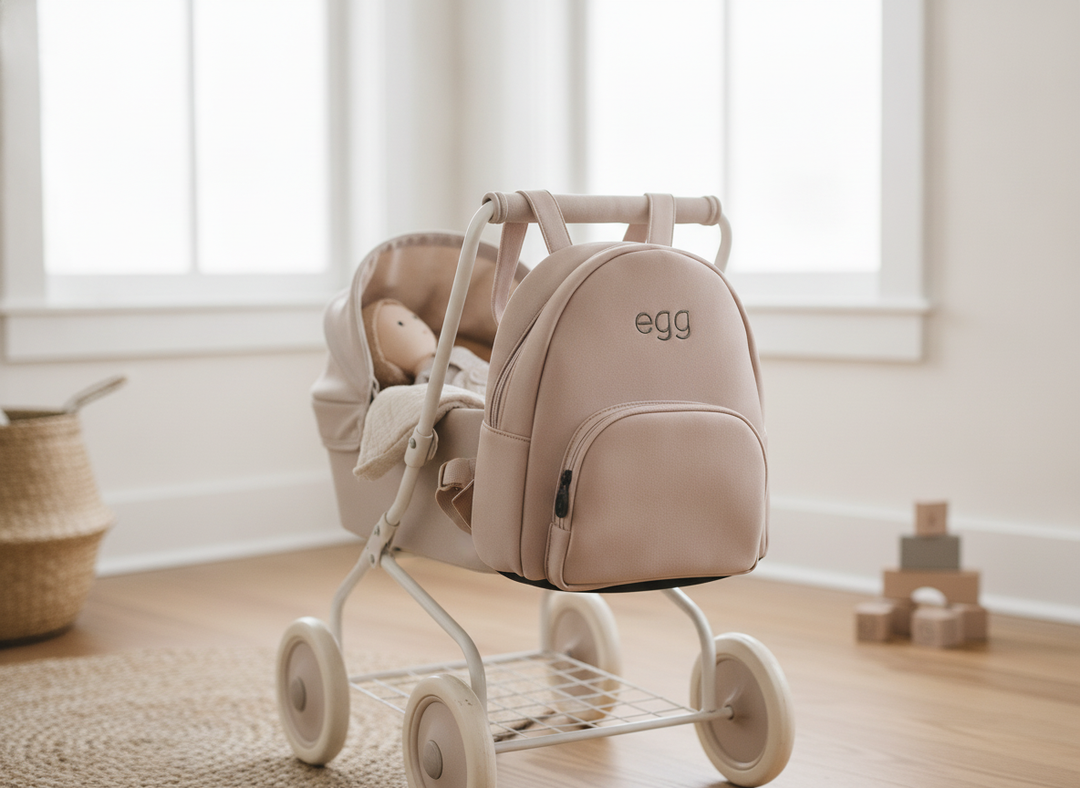 Roma Egg® Dolls Pram Bag in Feather, lifestyle shot shown fastened to a toy pram handle in a bright nursery playroom