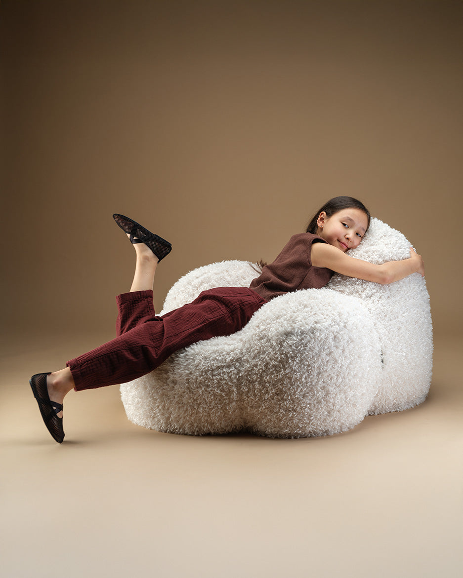 Child lounging on the Cream Wigiwama Momo Chair in high pile YETI fabric