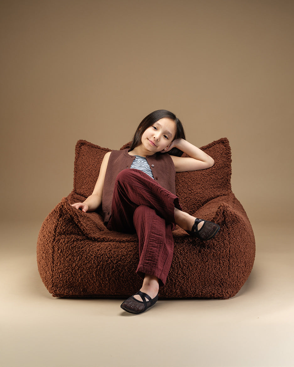Child seated in the Warm Hazel Wigiwama Club Chair, curly Teddy fabric